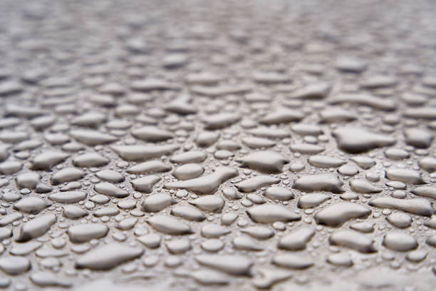 A macro shot shows countless blue water droplets on a smooth, reflective surface. The tight pattern creates texture, calm mood, and a cool, refreshing atmosphere.