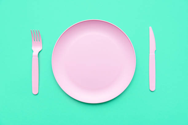 istock Pink plate and cutlery, above view, on a green table. 1389910484