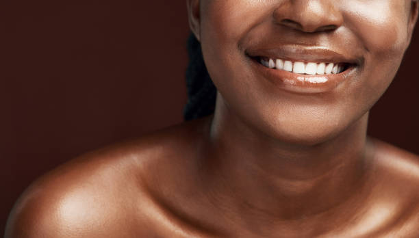 Studio shot of an attractive woman smiling brightly against a brown background A smile takes less energy then a frown black skin stock pictures, royalty-free photos & images