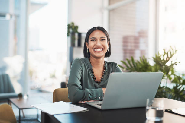 aufnahme einer jungen geschäftsfrau mit einem laptop in einem modernen büro - business women computer cheerful stock-fotos und bilder