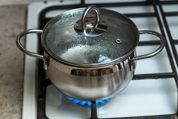 el agua en una olla de acero inoxidable se calienta con un gas - blue flame natural gas fireplace fotografías e imágenes de stock