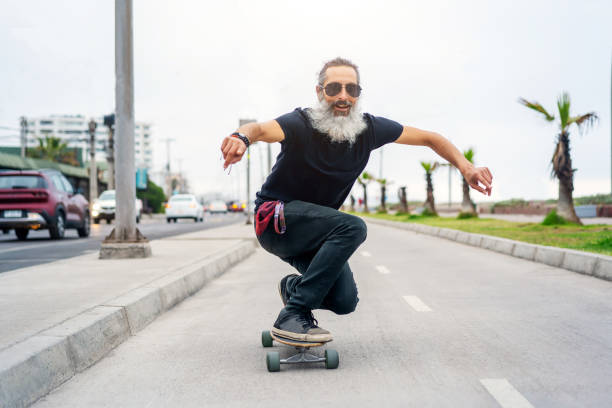 латинский старший мужчина скейтборд на велосипедной дорожке и веселье - skate стоковые фото и изображения