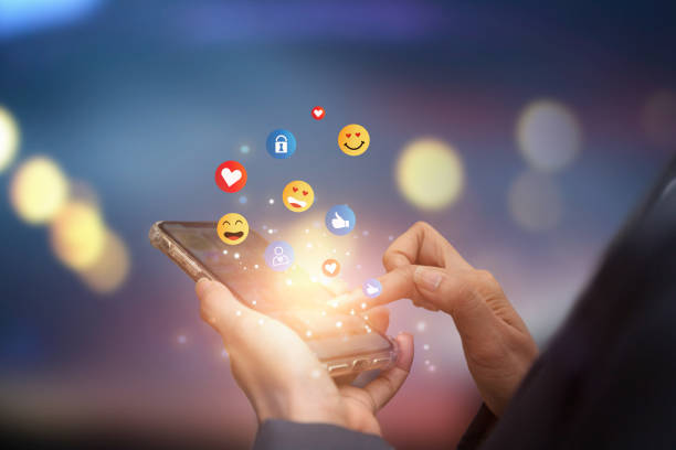 istock Young man using smartphone sending emojis. Mobile smartphone sending text messages emoji emoticon. 1389925990