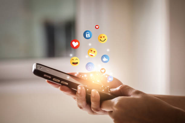 istock Young man using smartphone sending emojis. Mobile smartphone sending text messages emoji emoticon. 1389926007