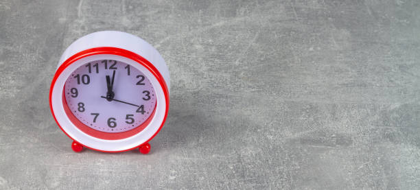 istock The red alarm clock shows the time on a gray background 1389927348