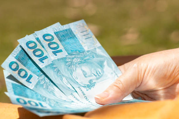 frauenhand mit brasilianischem geld, bündel von hundert reais-banknoten, finanzwirtschaftliches konzept, outdoor - human hand beak currency stack stock-fotos und bilder