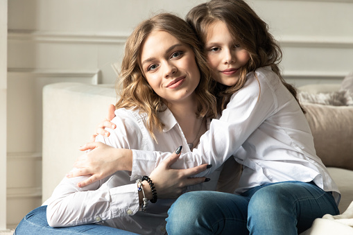 Real sisters hug, casual studio portrait of two beautiful European girls, soft selective focus