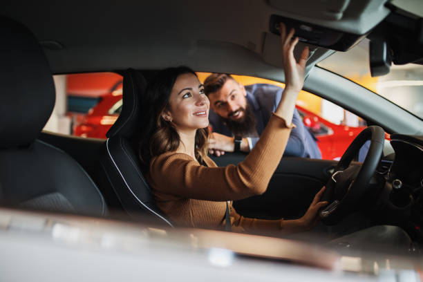 Car showroom Happy young couple is buying a new car at the car showroom. choosing between two cars stock pictures, royalty-free photos & images