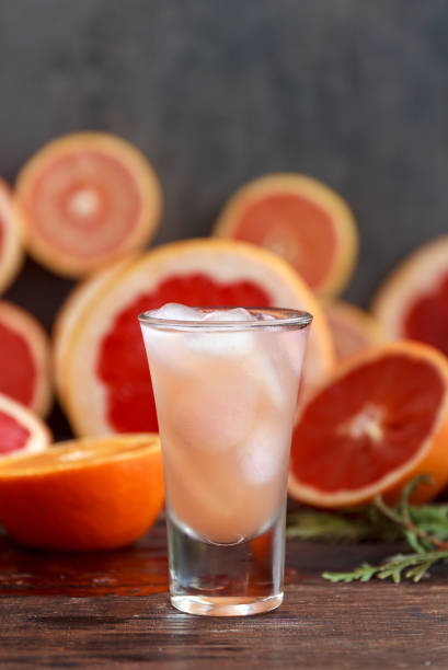 свежие грейпфруты нарезанные и высокий стакан, наполненный соком и водкой со льдом - crushed ice colors grape fruit стоковые фото и изображения
