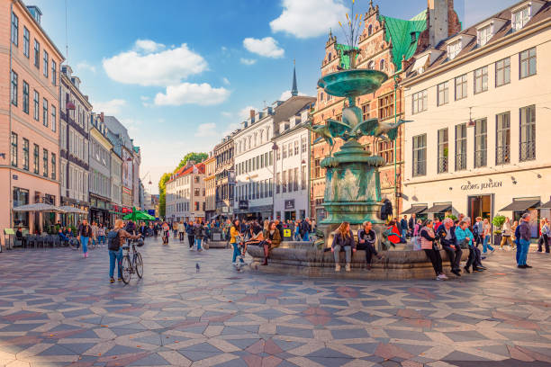 muchas personas caminan y se sientan cerca de la fuente de la cigüeña en la plaza amagertorv en la zona peatonal de strøget. copenhague, dinamarca - amager fotografías e imágenes de stock