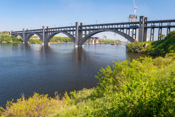 istock Preobrazhensky concrete arched bridge on Dnieper river in spring, view from Khortytsia island, Zaporozhye, Ukraine 1389937370