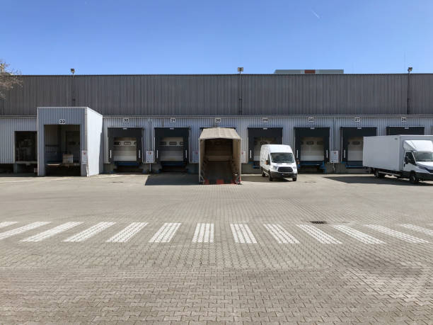 a truck and a delivery van at loading ramps of a warehouse stock photo