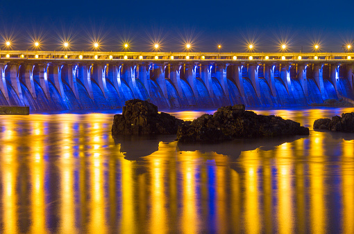 Evening view of Dneproges hydroelectric dam illuminated in blue and yellow colors, Dnieper river, Zaporozhye, Ukraine