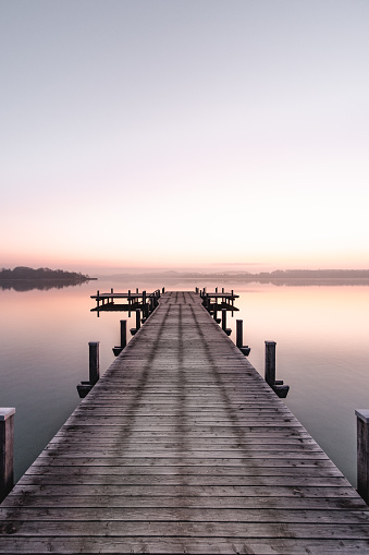 Beautiful sunrise at the Wörthsee in Bavaria, Germany with a beautiful clear, colorful sky. With a beautiful wooden footbridge. Enjoying the sun in Bavaria.