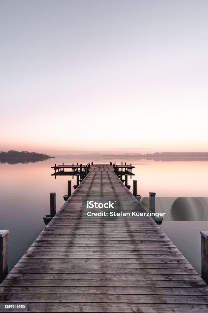 Beautiful sunrise at the Wörthsee in Bavaria, Germany with a beautiful clear, colorful sky. Beautiful sunrise at the Wörthsee in Bavaria, Germany with a beautiful clear, colorful sky. With a beautiful wooden footbridge. Enjoying the sun in Bavaria. Jetty Stock Photo