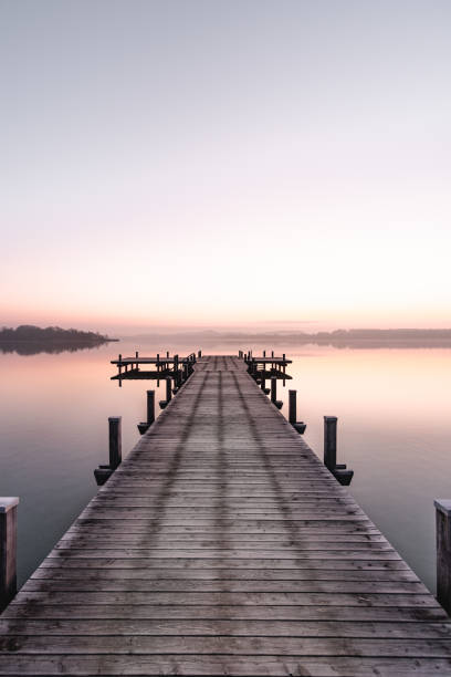 Beautiful sunrise at the Wörthsee in Bavaria, Germany with a beautiful clear, colorful sky. Beautiful sunrise at the Wörthsee in Bavaria, Germany with a beautiful clear, colorful sky. With a beautiful wooden footbridge. Enjoying the sun in Bavaria. floating dock stock pictures, royalty-free photos & images
