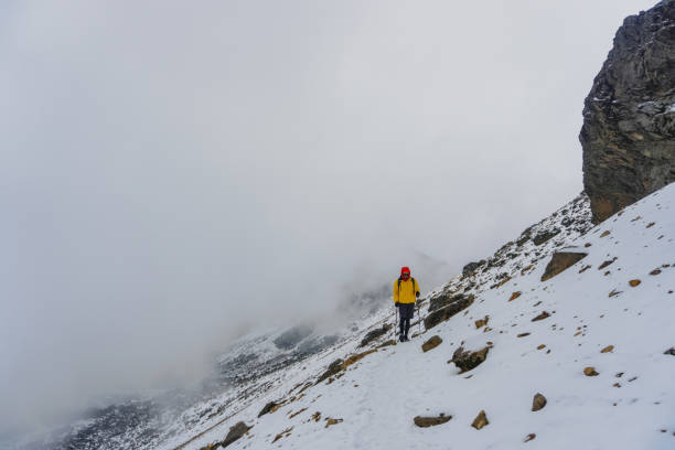 istock Man walking up snowy slope 1389948886
