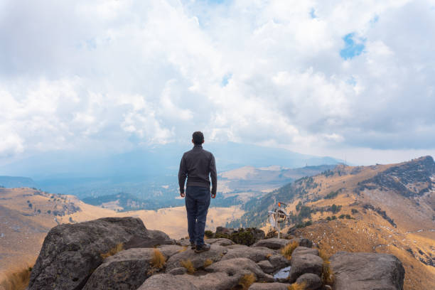 istock Man standing on a ledge of a mountain, enjoying the beautiful view 1389949081