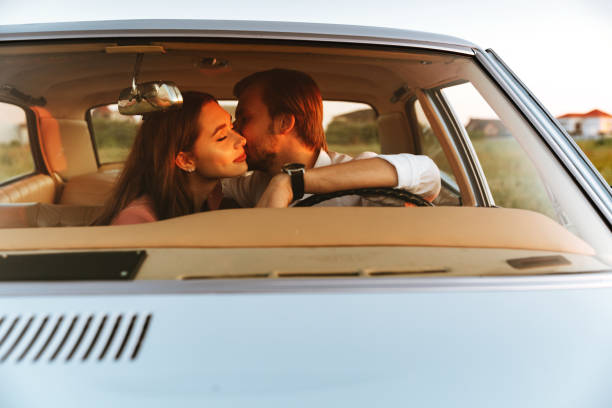 istock Young happy couple kissing while sitting together inside a car 1389954104
