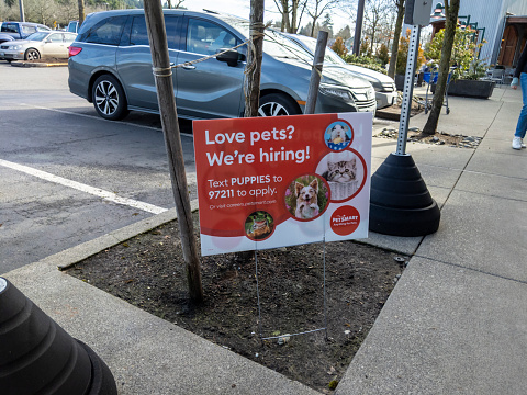 Woodinville, WA USA - circa February 2022: View of a Now Hiring sign outside of a Petsmart pet store on a bright, sunny day.