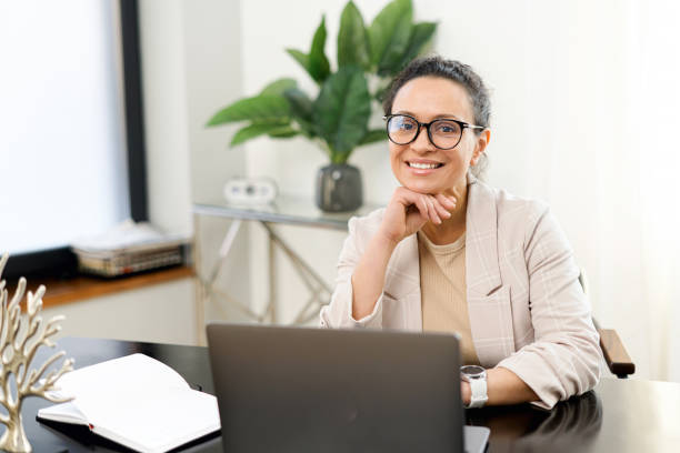 istock Confident middle-aged woman work with a laptop at the modern office 1389959533