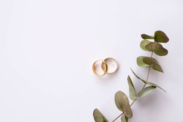 flowers and two golden wedding rings on white background.