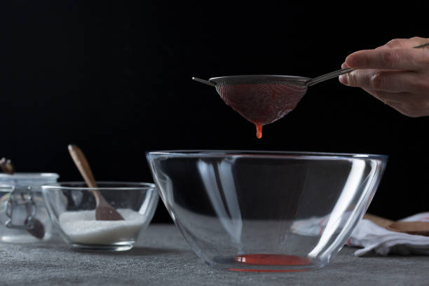 istock Woman straining strawberry jam through a sieve 1389964160