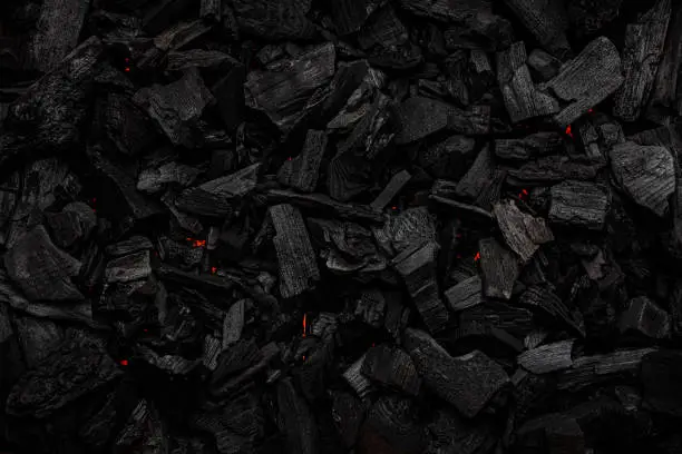 Photo of Charcoal with red streaks of heat. Textured dark background.