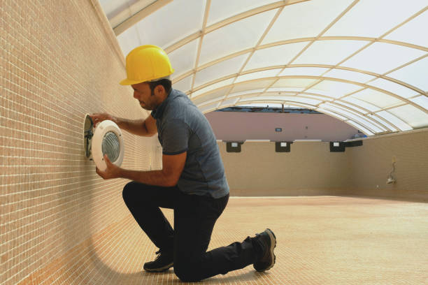istock electrician with screwdriver fixes light bulb in an empty swimming pool under construction 1389966276