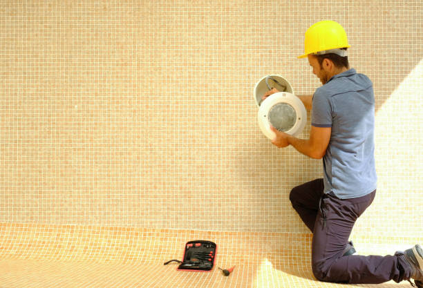 istock electrician with screwdriver fixes light bulb in an empty swimming pool under construction 1389966311