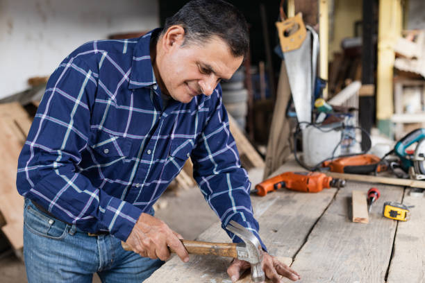 istock Hispanic carpenter nailing into wood - worker man with carpentry tools - man hammering 1389970280