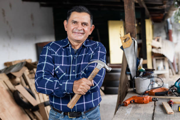 retrato de carpinteiro latino na oficina dele segurando um martelo-homem hispânico em sua oficina de carpintaria - home improvement work tool hammer portrait - fotografias e filmes do acervo