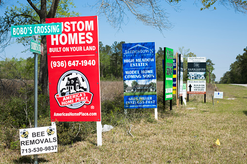 Home builder's advertisements on the side of the road in sought after properties in the area of Bobo's Crossing near Magnolia, Texas.  Properties are near the new high school and two new shopping centers under construction.  Located on the outskirts of The Woodlands, this area is booming and home prices have skyrocketed.\nApril, 2022.