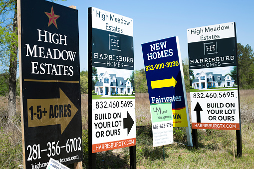 Home builder's advertisements on the side of the road in sought after properties in the area of Bobo's Crossing near Magnolia, Texas.  Properties are near the new high school and two new shopping centers under construction.  Located on the outskirts of The Woodlands, this area is booming and home prices have skyrocketed.\nApril, 2022.