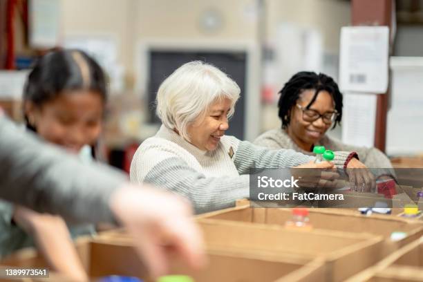 Volunteers Packing At A Local Food Bank Stock Photo - Download Image Now - Food Bank, Volunteer, Charitable Donation
