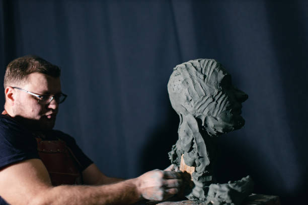 istock Man sculptor creates sculpt bust clay human woman sculpture. Statue craft creation workshop 1389975893