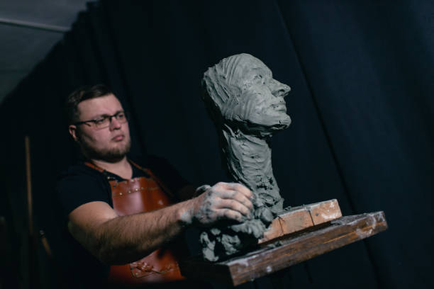 istock Man sculptor creates sculpt bust clay human woman sculpture. Statue craft creation workshop 1389975895