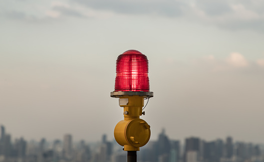 Linterna roja de luces de obstrucción montadas en la azotea del edificio alto de gran altura para garantizar la seguridad de los vuelos y advertir el peligro para el avión en el fondo de la vista de la ciudad. photo