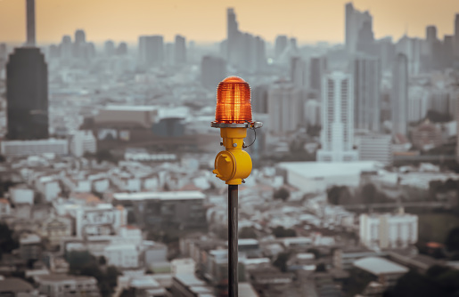 Linterna roja de luces de obstrucción montadas en la azotea del edificio alto de gran altura para garantizar la seguridad de los vuelos y advertir el peligro para el avión en el fondo de la vista de la ciudad. photo