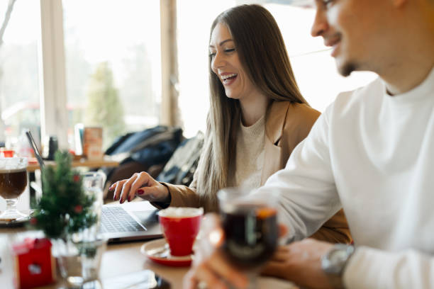 istock Cheerful young couple using laptop while sitting in cafe 1389979319