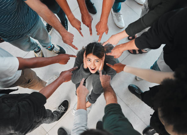 foto de una mujer joven que experimenta una enfermedad mental mientras está rodeada de personas en su interior - avergonzamiento fotografías e imágenes de stock