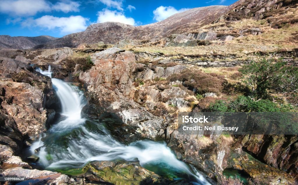 Waterfalls next to the Watkin Path en route to Mount Snowdon,Snowdonia national Park,Wales,UK. Clear fresh mountain spring rain water,flowing,rushing down from the Welsh,Snowdonian mountains in North Wales,on a clear sunny day in mid March. Footpath Stock Photo