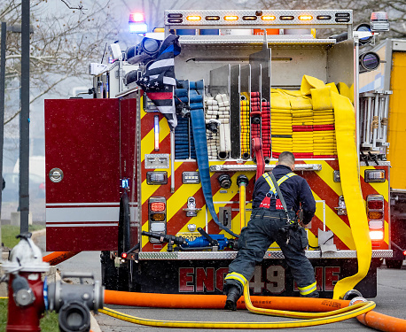Plainsboro, NJ, USA - March 28, 2022: Back of the firetruck with firefighter and hoses equipment ready to use during accident
