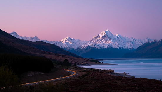 Car light trails on Mt Cook road. Snow-capped Mt Cook at sunset, South Island, New Zealand