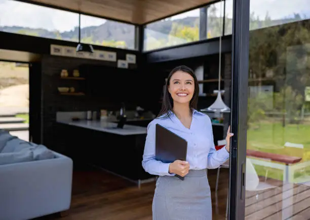 Happy Latin American real estate agent showing a property and smiling - business concepts