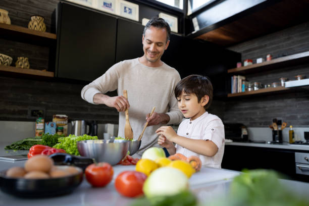 papà e presto cucinano insieme in cucina a casa - iberico sud europeo foto e immagini stock