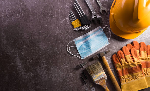 istock Happy Labor day concept during coronavirus disease (Covid-19). Different construction tools and medical mask on dark stone background. 1389994716