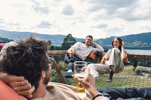 Group of Latin friends talking to each other and toasting with their drinks in a glamping while enjoying their vacations - background of mountains and sky Neusa - Colombia.
