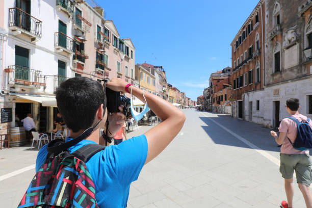 istock boy with a backpack on his shoulders while photographing Venice almost deserted due to the lockdown 1390003535