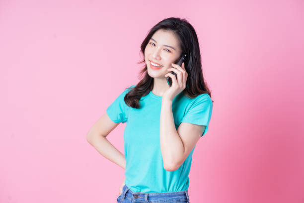 istock Young Asian woman using smartphone on pink background 1390005787